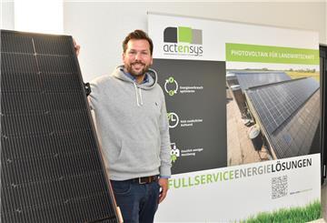 Mann steht neben einer Photovoltaikanlage