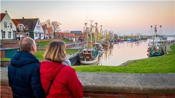 Touristen schauen auf die Krabbenkutter am Hafen.