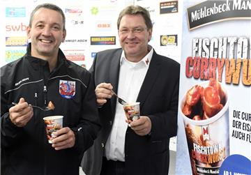 Trainer Thomas Popiesch (links) und  Mühlenbeck-Chef Gebhard Buck probieren die neue Pinguins-Currywurst.