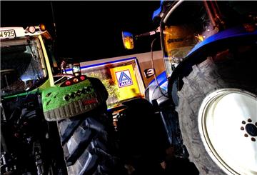 Traktoren stehen vor einem LKW in der Zufahrt zum Zentrallager von Aldi. Mit rund 200 Fahrzeugen protestieren Bauern vor dem Aldi-Lager in Hesel (Landkreis Leer).