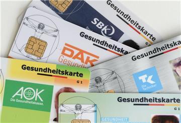 Gesundheitskarten verschiedener Krankenkassen liegen auf einem Tisch. 