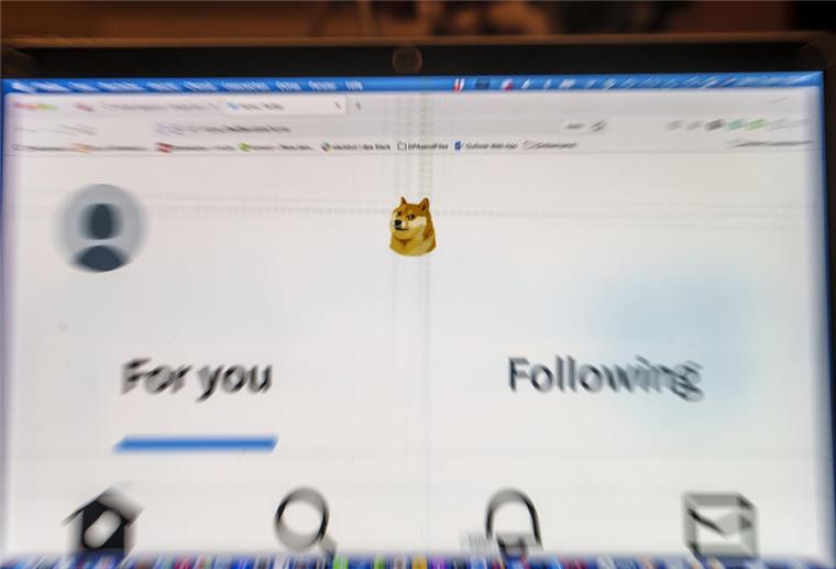 Twitter-Logo durch Hundekopf ersetzt - Symbol für Dogecoin Auf einem Laptop-Display ist die Startseite von Twitter zu sehen, die anstelle des Twitter-Logos das Symbol der Digitalwährung Dogecoin zeigt.
