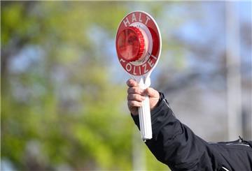 Ein Polizist hält eine Warnkelle in die Luft. 
