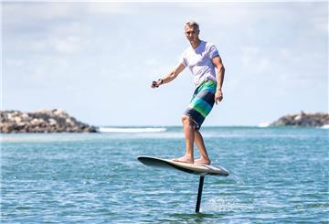 Über eine Fernbedienung in der Hand bedient der Surfer den Elektromotor unter Wasser.