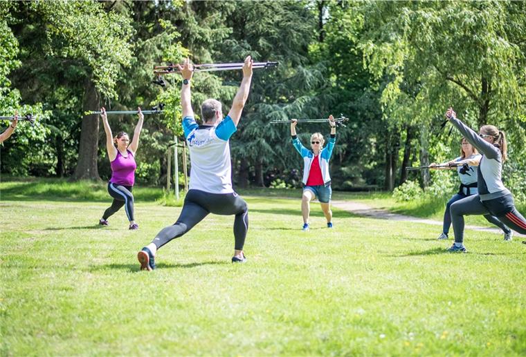 Übungsleiter Fred Ludwig von Havenyoga und seine Teilnehmerinnen absolvieren verschiedene Yogaübungen mit Nordic-Walking-Stöckern.