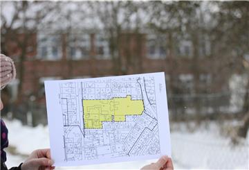 Ein  Mädchen hält einen Plan mit einer gelben Flächen-Markierung in der Hand.