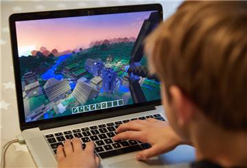 Ein Kind sitzt vor einem Laptop und spielt Minecraft.
