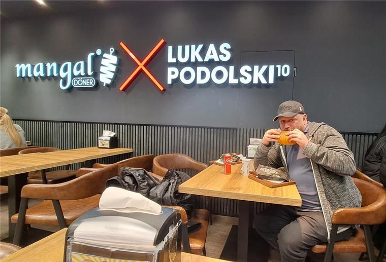 Ein Mann isst einen Döner Kebab in einem Laden von Ex-Fußballstar Lukas Podolski.