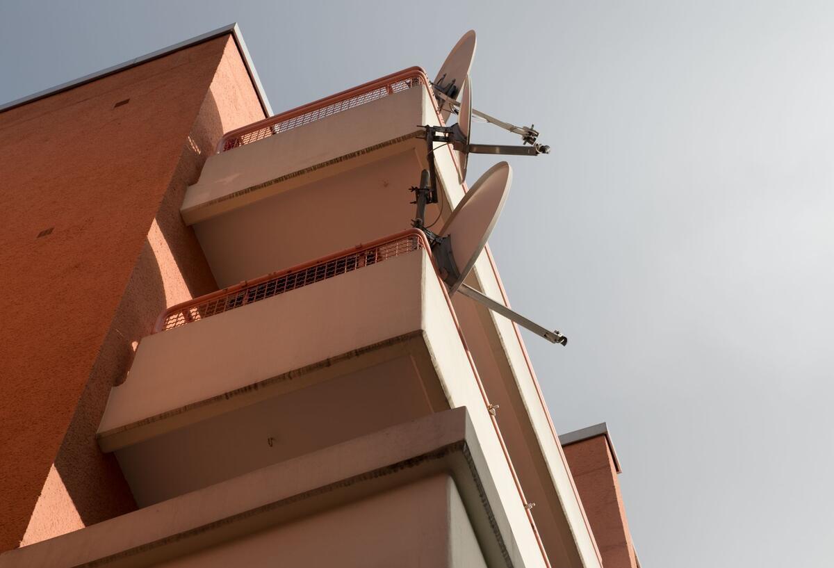 Diese 6 Balkon-Regeln sollten alle Mieter kennen Mehrere Balkone mit Satellitenschüsseln.
