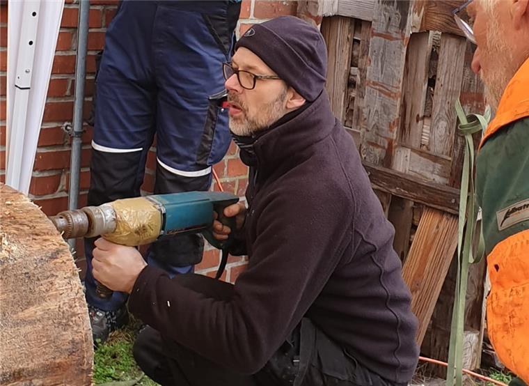 Imkerverein Wesermünde baut Bäume für die Bienen Unter den wachsamen Augen seiner Kollegen bohrt Michael Gerdes (hockend) Löcher in den Stamm. Sie dienen als Vorbereitung zum Aushöhlen des Stammes.