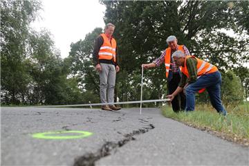 Unternehmer Christian Lürßen (links), CDU-Kreistagsabgeordneter Claus Götjen und Ortsvorsteher Bernd Beckmann (CDU, rechts) vermessen die Stelle, an der die Straße abgesackt ist.