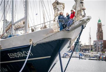 Zwei junge Frauen und ein junger Mann stehen vorne auf einem Schiff.