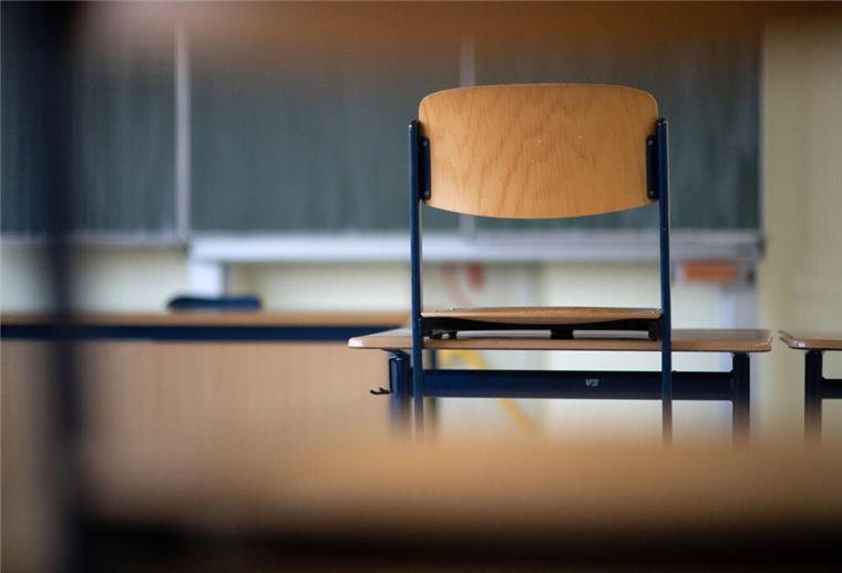 Ein Stuhl steht in einem Klassenzimmer auf dem Tisch. 