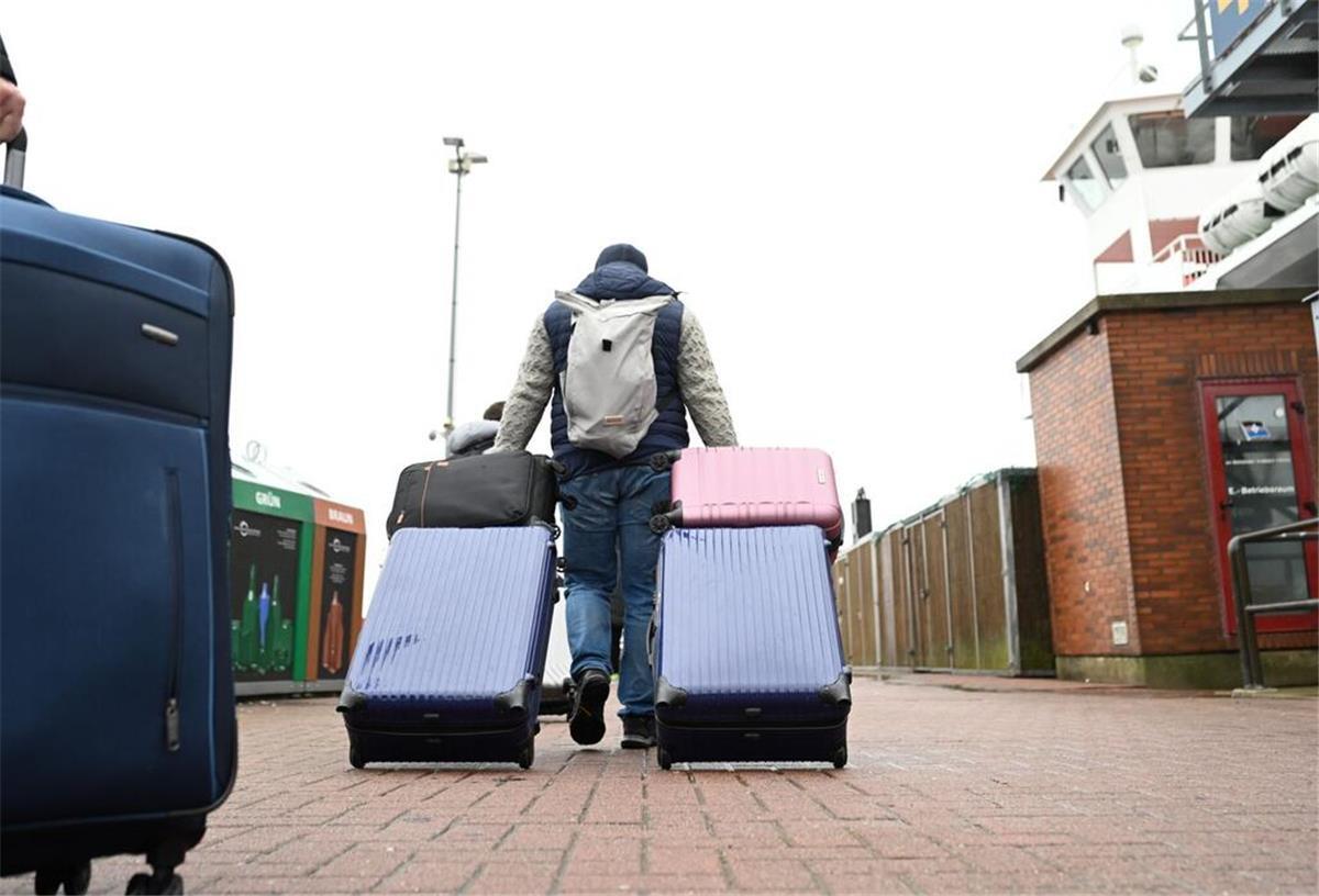 Ferien beginnen: An der Küste wird es dieses Wochenende voll Urlauber laufen am Fähranleger mit ihrem Gepäck zur Fähre.