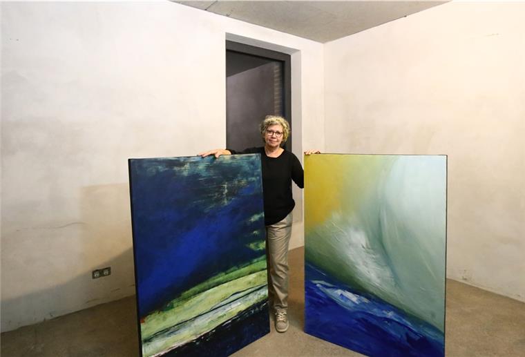 Ursula Peschke-Maßmann mit zwei Bildern im neuen Müllerhaus in Burhave. Noch sind die Wände roh und bilden einen Kontrast zu den Kunstwerken.