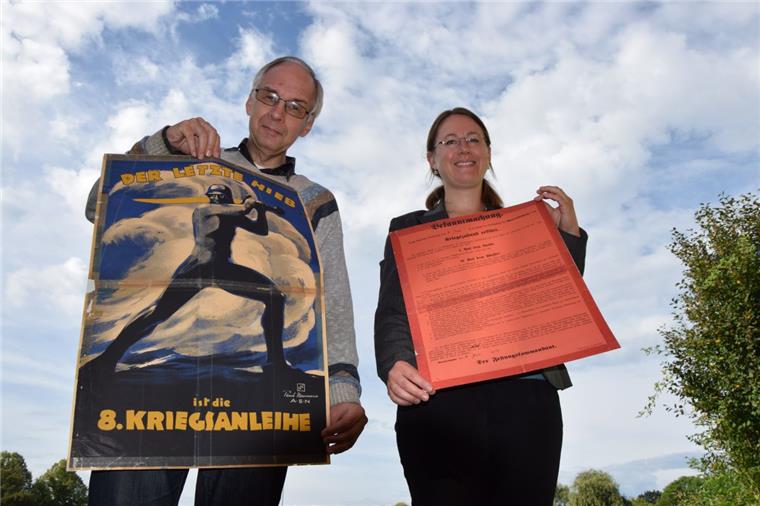 Uwe Jürgensen zeigt den Aufruf zur 8. Kriegsanleihe vom März 1918. Schlagzeile: „Der letzte Hieb“. Ein anderer Werbespruch, um mit Hilfe des Volkes die Kriegskasse zu füllen, lautete: „Gold gab ich für Eisen“. Dr. Julia Kahleyß hält die Bekanntmachung zum Kriegszustand vom 31. Juli 1914 in ihren Händen. Aufgerufen wird darin unter anderem, den vaterländischen Pflichten nachzukommen.