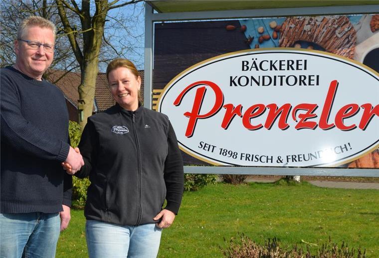 Zwei Menschen geben sich die Hand und stehen vor dem Bäckerei Prenzler Schild.