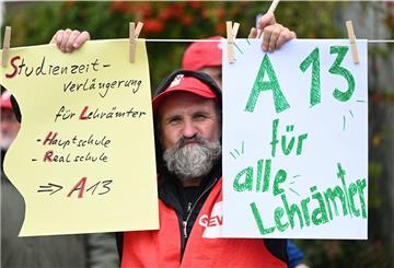 Ein Mitglied der Gewerkschaft Erziehung und Wissenschaft hält Plakate hoch.