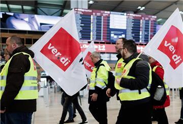 ARCHIV - 14.03.2024, Brandenburg, Schönefeld: Mitarbeiter des Luftsicherheitspersonals demonstrieren mit Fahnen der Dienstleistungsgewerkschaft Verdi in der Abflughalle im Terminal 1 des Flughafens BER. (zu dpa: «67.000 Passagiere betroffen - Warnstreik am BER läuft») Foto: Carsten Koall/dpa +++ dpa-Bildfunk +++