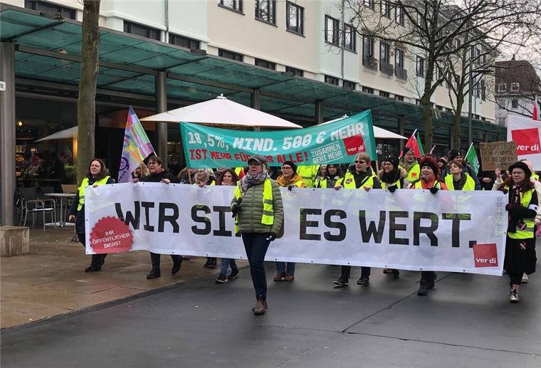 Warnstreiks in Bremerhaven: Demonstranten ziehen durch die Stadt Menschen laufen durch die Straßen und halten Banner hoch.
