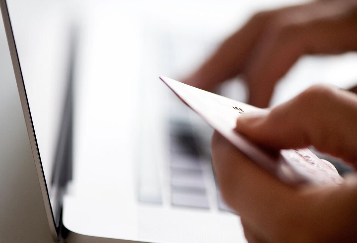 Beliebter Kreditkartenanbieter ändert Modell: Vielen Kunden droht Kündigung Eine Person sitzt mit einer Kreditkarte vor dem Laptop.