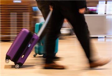 Menschen gehen im Terminal 1 am Flughafen Berlin Brandenburg mit Gepäck durch die Haupthalle. 