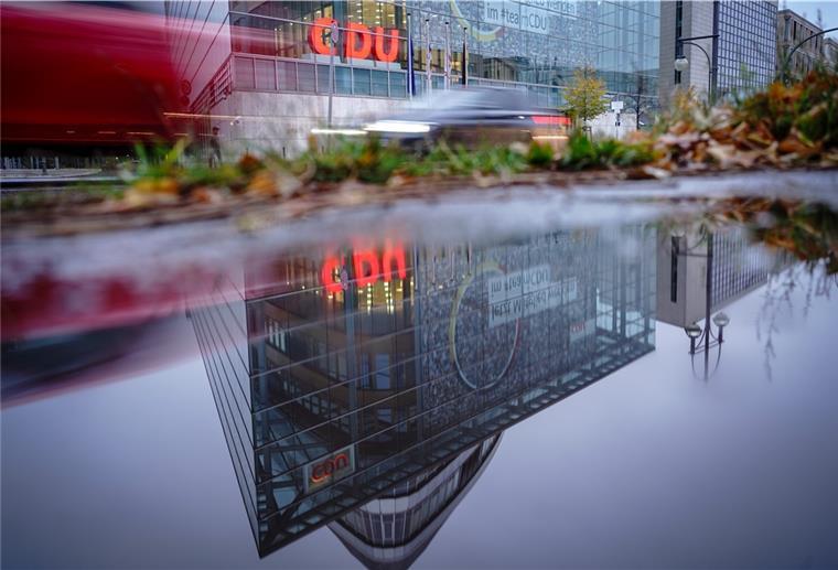 Die CDU-Parteizentrale, das Konrad-Adenauer-Haus, spiegelt sich am frühen Morgen in einer Regenpfütze.