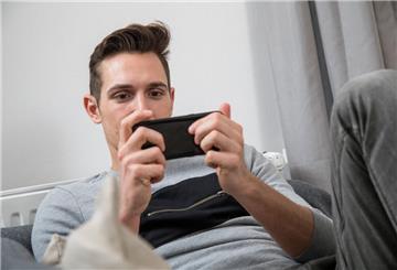 Ein Mann sitze auf einer Couch und hängt vor dem Handy