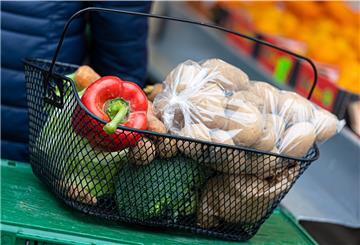 Der mit Paprika, Broccoli, Kartoffeln und anderen Lebensmitteln gefüllte Korb einer Kundin steht auf einer Kiste an einem Stand auf einem Wochenmarkt.