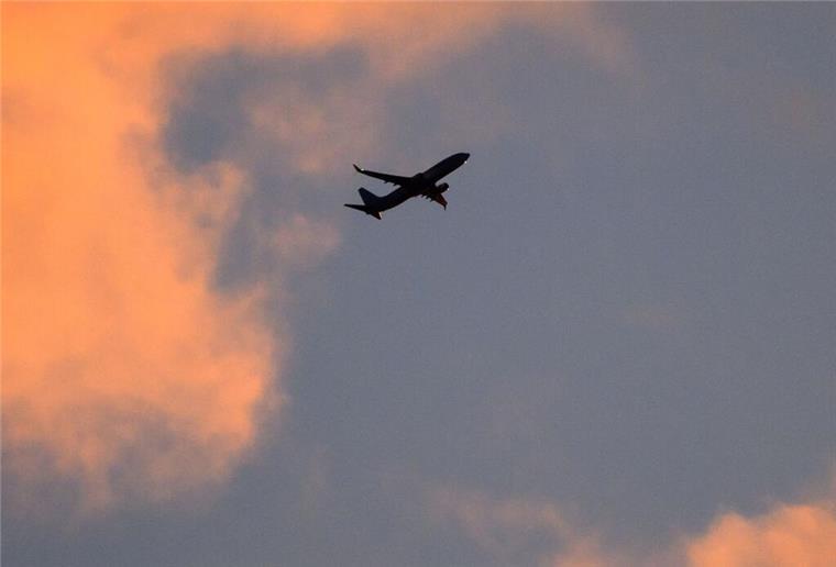 Eine Boeing 737 zeichnet sich vor dem vom Sonnenaufgang verfärbten Morgenhimmel ab.
