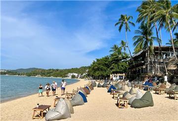 Ein Strand in Thailan mit Meer, Palmen und Sand und Sitzmöglicgkeiten