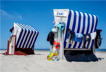 Das Sandspielzeug einer Familie steht bei sonnigem Wetter neben einem Strandkorb am Strand der Nordsee.