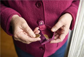 Eine ältere Frau hält ein fast leeres Portemonnaie in der Hand.