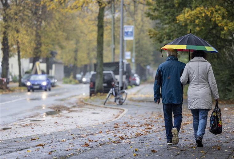 Regenschauer und Gewitter: An der Nordseeküste wird es ungemütlich Passanten mit Regenschirm sind im Regen auf dem Gehweg unterwegs.