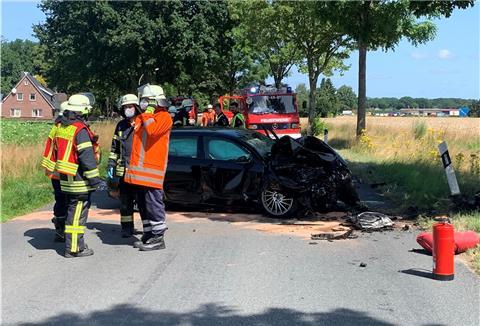 Vier Feuerwehrleute stehen vor einem Unfallwagen
