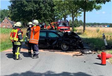 Vier Feuerwehrleute stehen vor einem Unfallwagen
