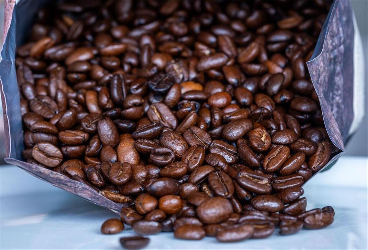 Kaffeehersteller schlägt Alarm! Preise steigen weiter, Verbrauch bleibt hoch Geröstete Kaffeebohnen liegen vor einer Tüte