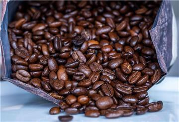 Geröstete Kaffeebohnen liegen vor einer Tüte