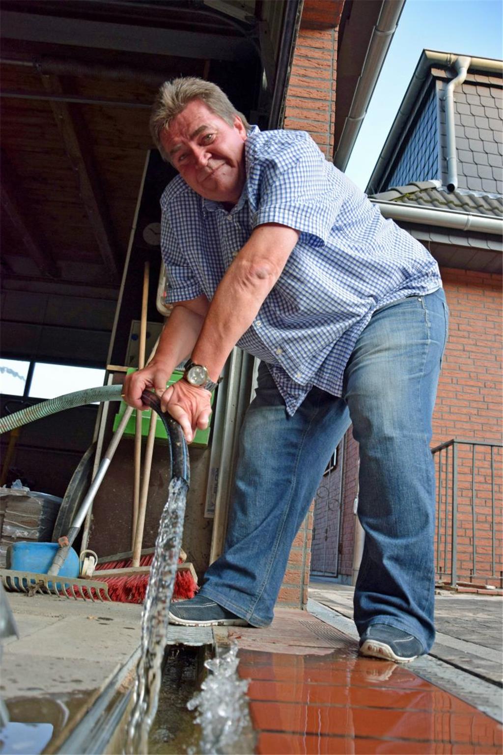 Volker Recht hebt den Schlauch aus der Ablaufrinne. 10 Liter Wasser sprudeln inn...