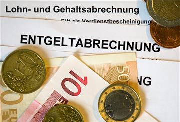 Auf Lohn- und Gehaltsabrechnungen (Entgeltabrechnungen) liegen Euromünzen und Eurogeldscheine,
