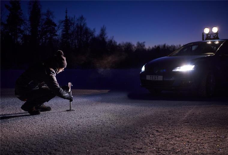 eine Frau misst den Bremsweg eines Autos mit Winterreifen auf verschneiter Strecke