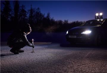 eine Frau misst den Bremsweg eines Autos mit Winterreifen auf verschneiter Strecke