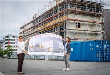 Vor dem Erweiterungsbau des Deutschen Auswandererhauses zeigen Direktorin Dr. Simone Eick (links) und die wissenschaftliche Mitarbeiterin Lina Falivena, wie das Gebäude später aussehen soll.