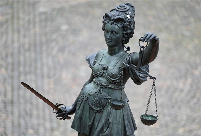 Eine Figur hält ein Schwert und eine Waage.
