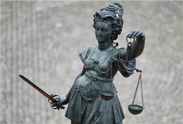 Eine Figur hält ein Schwert und eine Waage.
