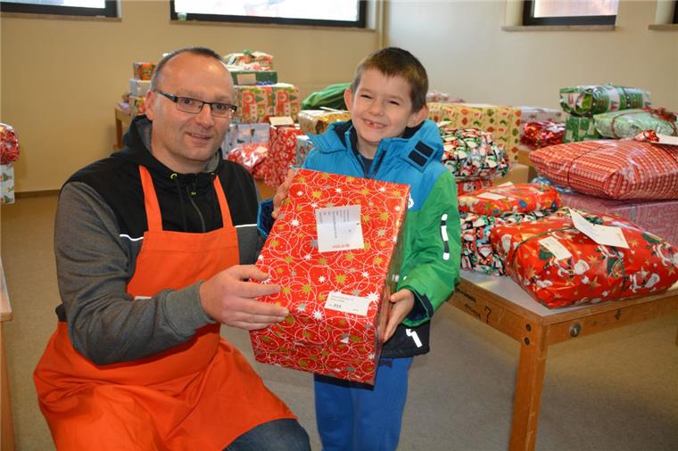 Viele glückliche Kinderaugen bei der NZ-Wunschbaumaktion im Cuxland Vorweihnachtliche Bescherung beim Ausgabetag der Beerster Tafel im Evangelischen Gemeindehaus: Pastor Dirk Glanert überreicht Lukas das für ihn bestimmte Weihnachtspäckchen.