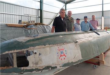 Fünf Männer stehen in einer Halle am Schwimmer des Flugzeugs Arado.