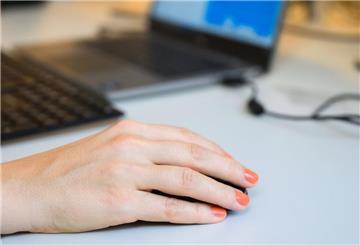 Eine Frau bedient eine Computermaus an einem Schreibtisch