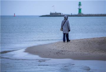 Eine Person steht am Strand vor dem Meer und trägt eine dicke Winterjacke. Der Winter 2024/25 war im Nordwesten außergewöhnlich mild.