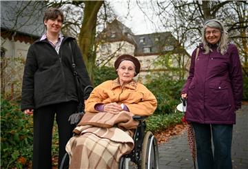 Waltraud Kosak (Mitte) ist mit ihrem Porträt und dem ihres verstorbenen Mannes Erich Teil der Fassade des neuen Traktes des Auswandererhauses. Heute freut sich die 94-Jährige, wenn Tochter Carola (rechts) und Enkelin Bettina sie im Lotte-Lemke-Haus besuchen kommen und eine kleine Runde durch den Park mit ihr drehen. Das Bild entstand vor dem Corona-Lockdown. Foto Scheschonka
